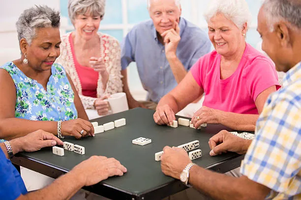 Older adults playing dominoes together around a table
